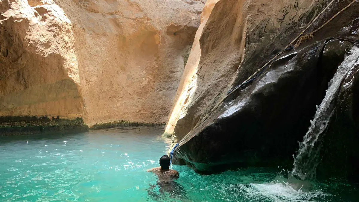 A swimmer below the waterfall at the far end of the Wadi Shab pools